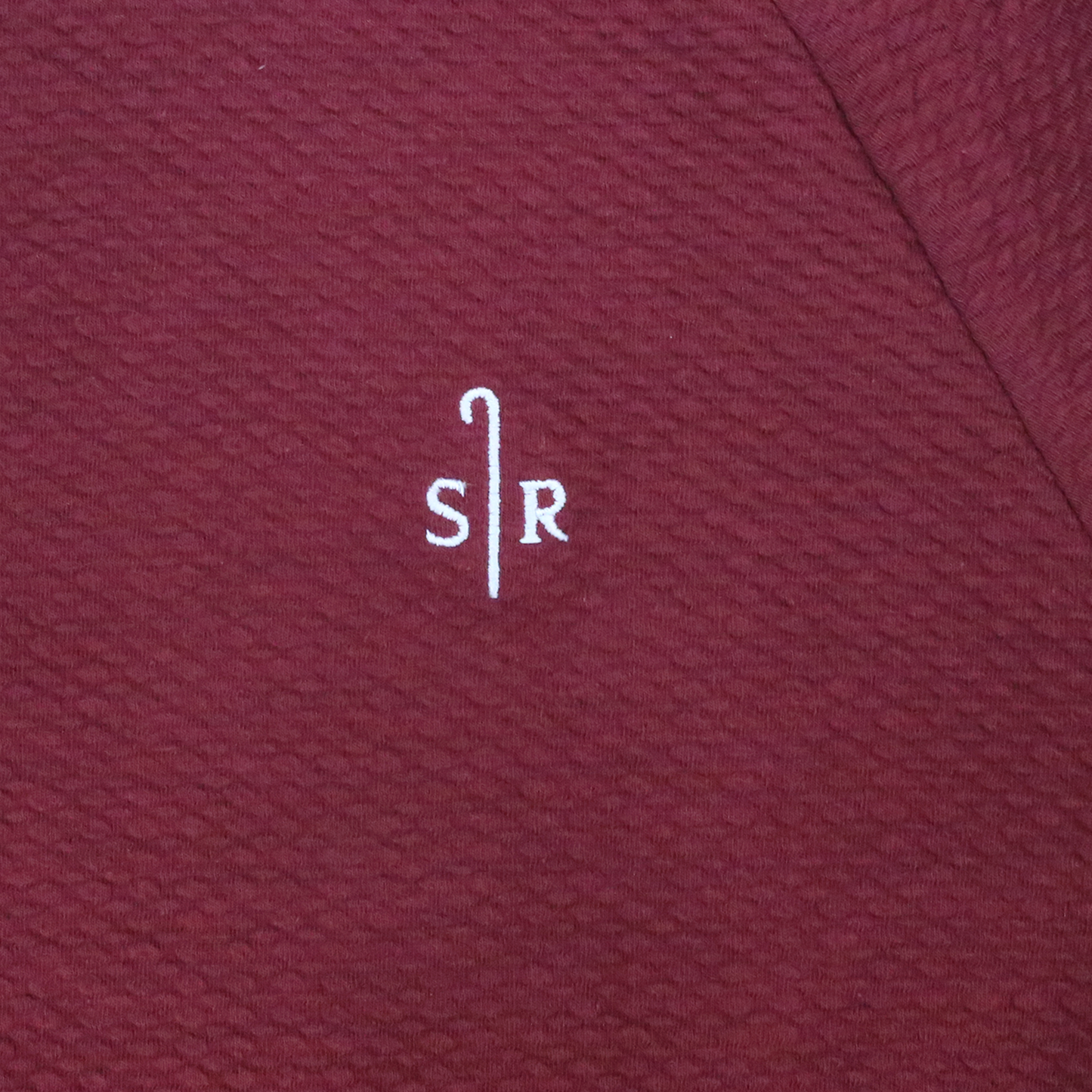 Close up of the Maroon textured fabric with white embroidery Sheep Ranch logo.