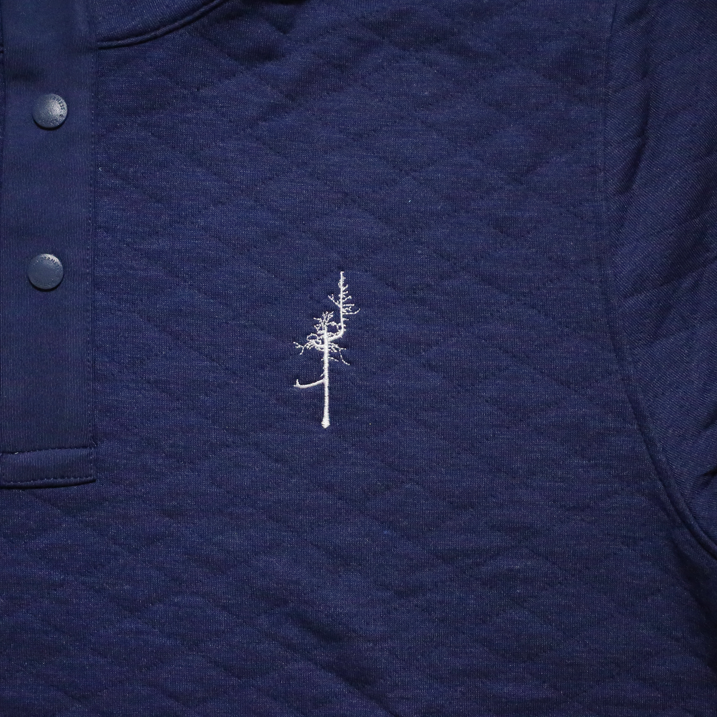 Close up of the white embroidered Ghost Tree and the navy quilted fabric.