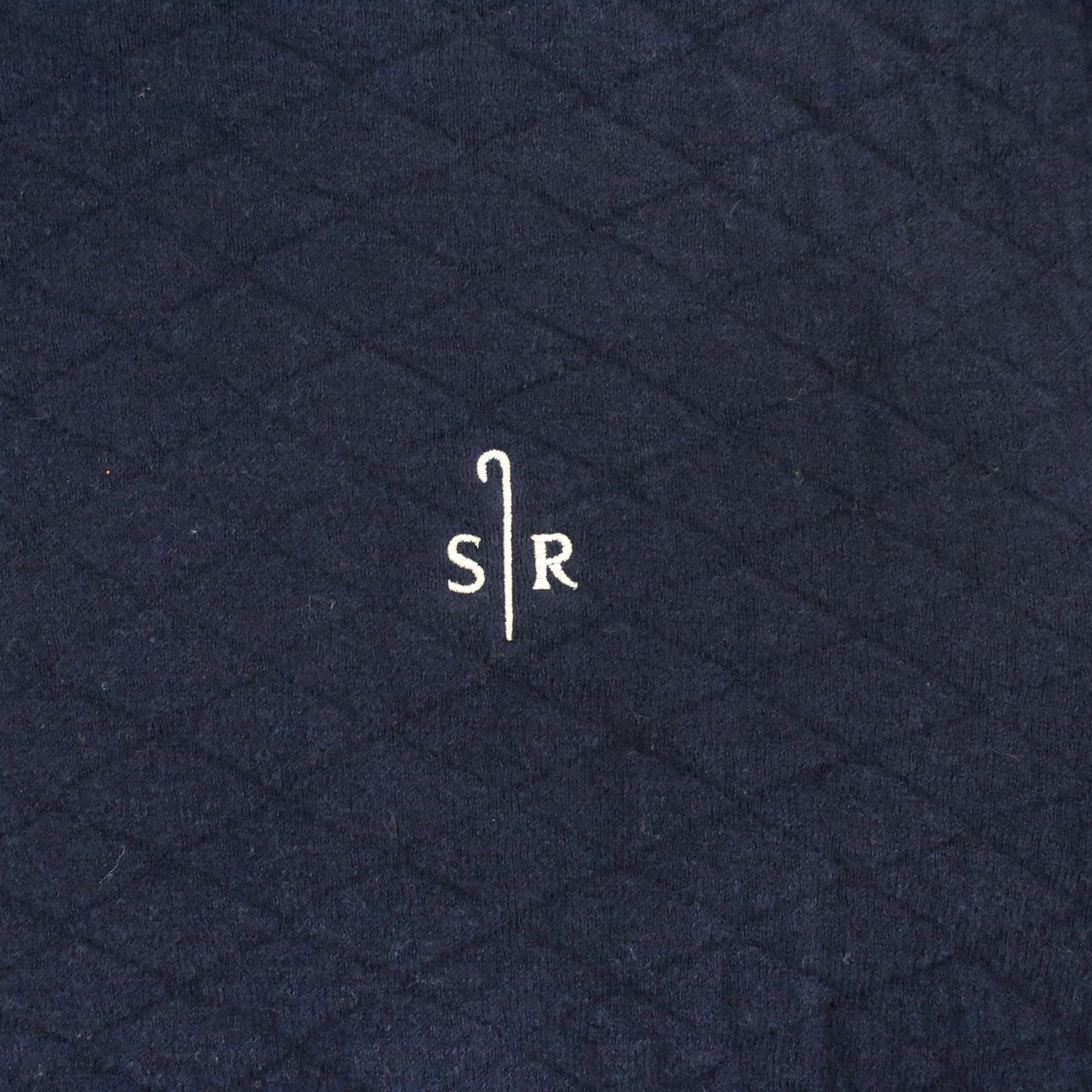 Close up of Navy jacquard-knit crewneck sweater hoodie. Sheep Ranch logo embroidered in white. 