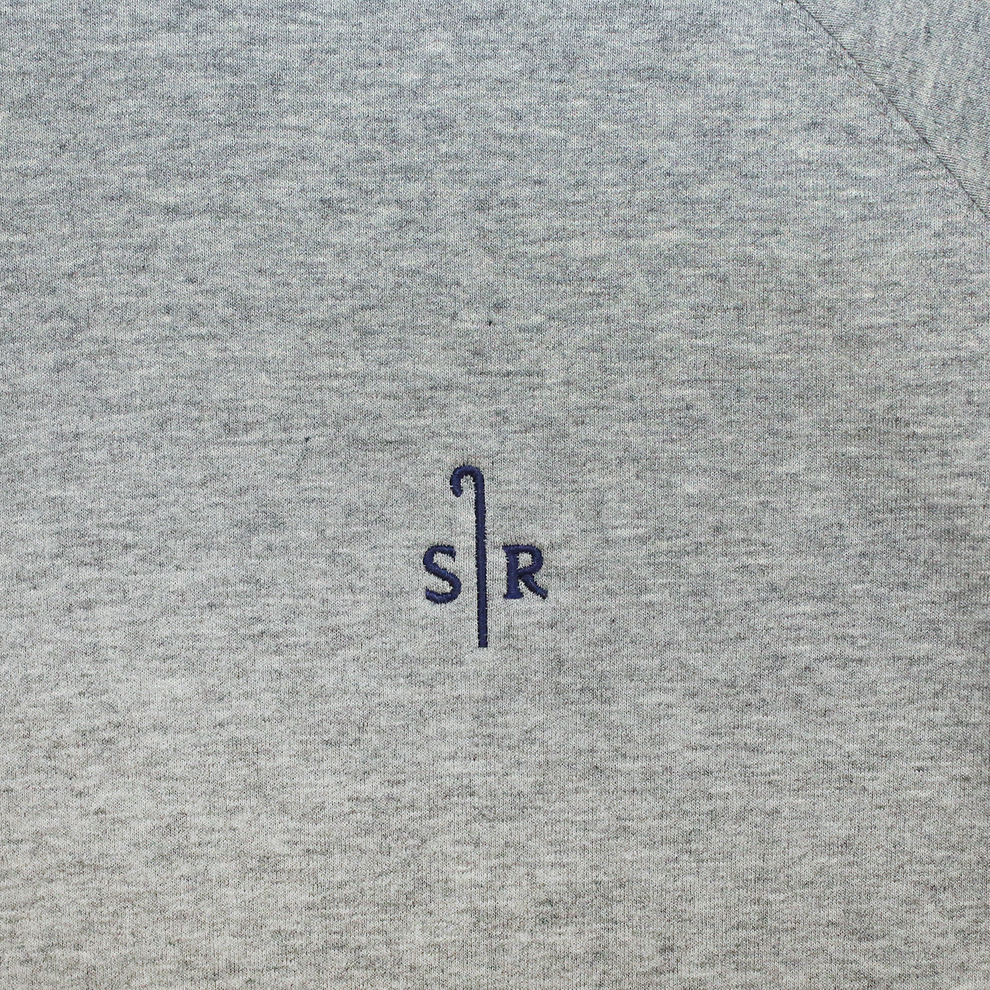 Close up of gray sweatshirt fabric with embroidered Sheep Ranch logo.