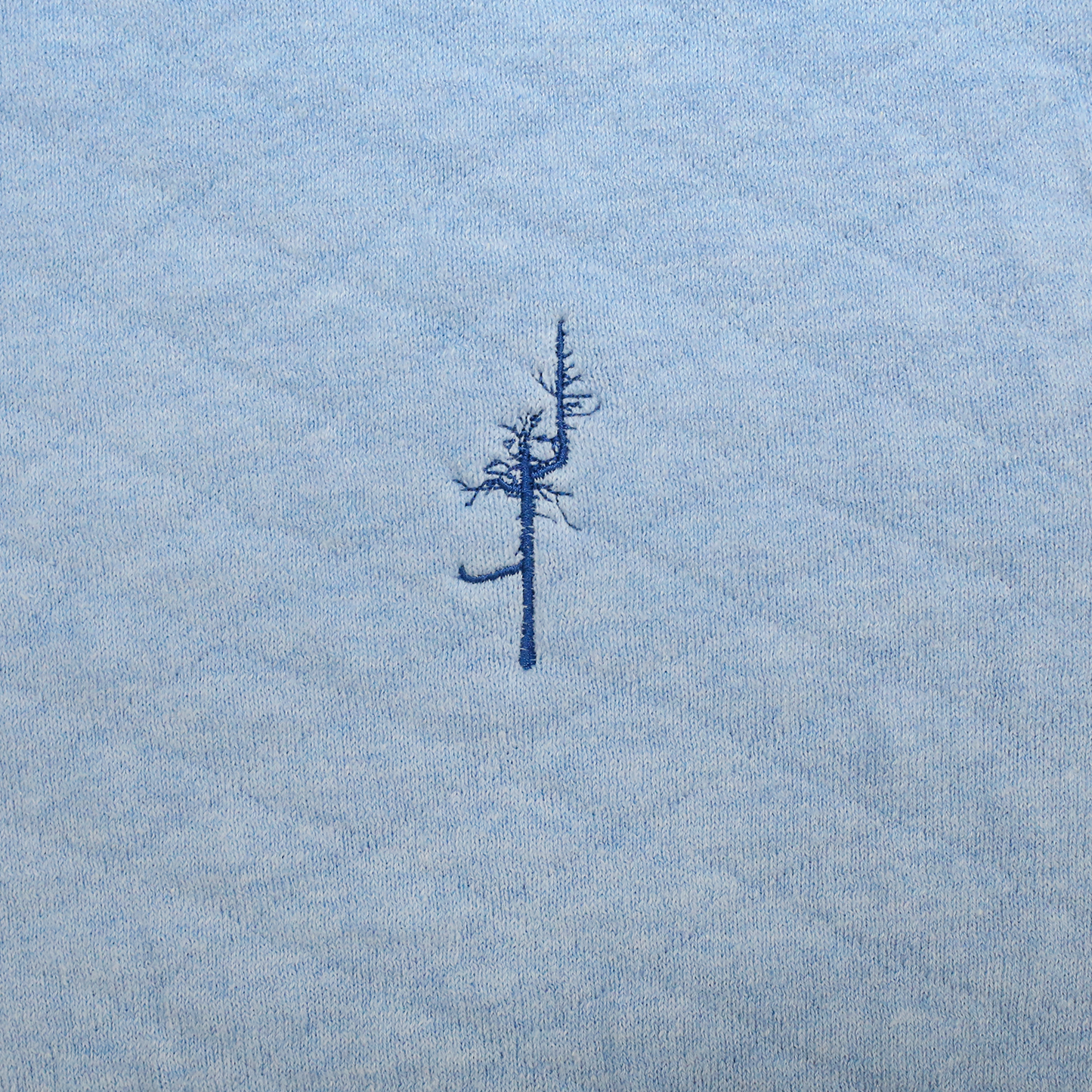 Close up Light Blue jacquard-knit with Ghost Tree logo embroidered in blue.