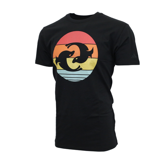 A black Adidas crew-neck t-shirt featuring a large circular graphic on the center chest. The graphic depicts the Pacific Dunes harbor seals logo silhouetted in sunset composed of horizontal bands in red, orange, yellow, and light blue.